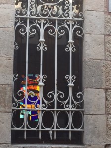 Stained glass window seen through the grate of a synagogue window.